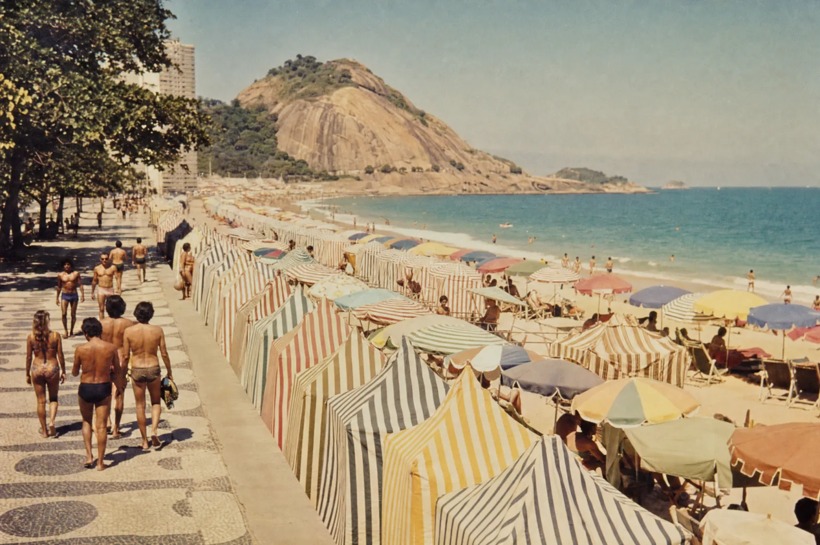 Calçadão de praia nos anos 70 com barracas listradas coloridas